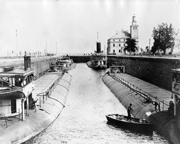 Stern view, lower left corner, towing steamer to the upper right, downbound in the Soo Locks, c. 1890s.