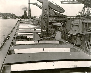 William G. Mather - Hulett ore unloaders, hatches piled alongside, and the &#034;iron deckhand&#034; which lifts and moves the several ton hatch covers, c.1950s.