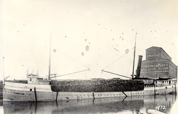 Portside view, with a deck cargo of lumber, grain elevator in rear, early 1900s.