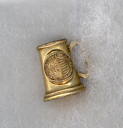 Golden pin with UofD logo shaped like a mug